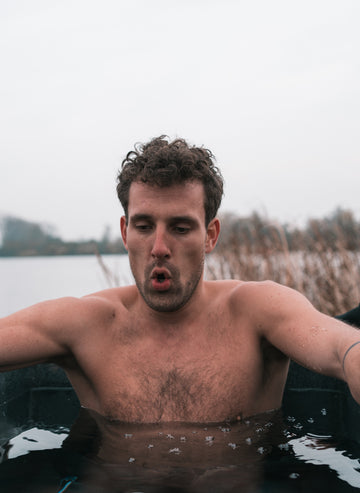 man sitting in ice bath outdoors